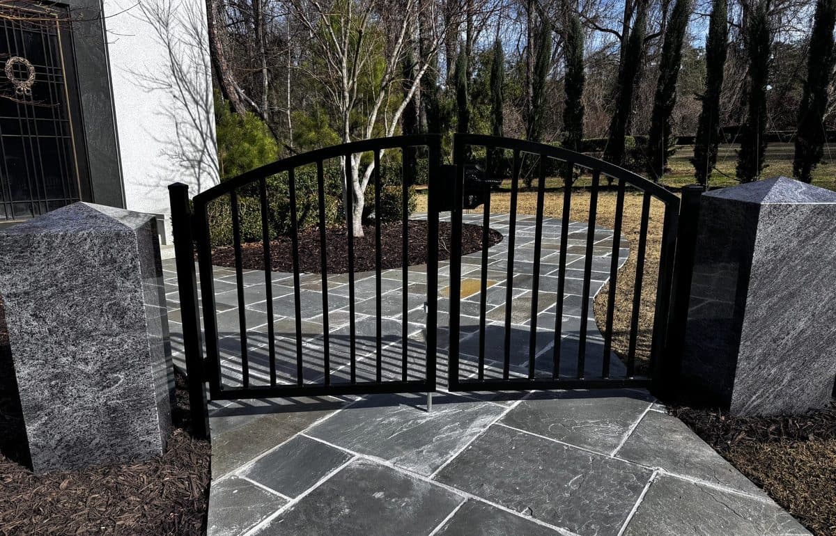 Black ornamental arched gate with granite pillars at residential property in Georgia